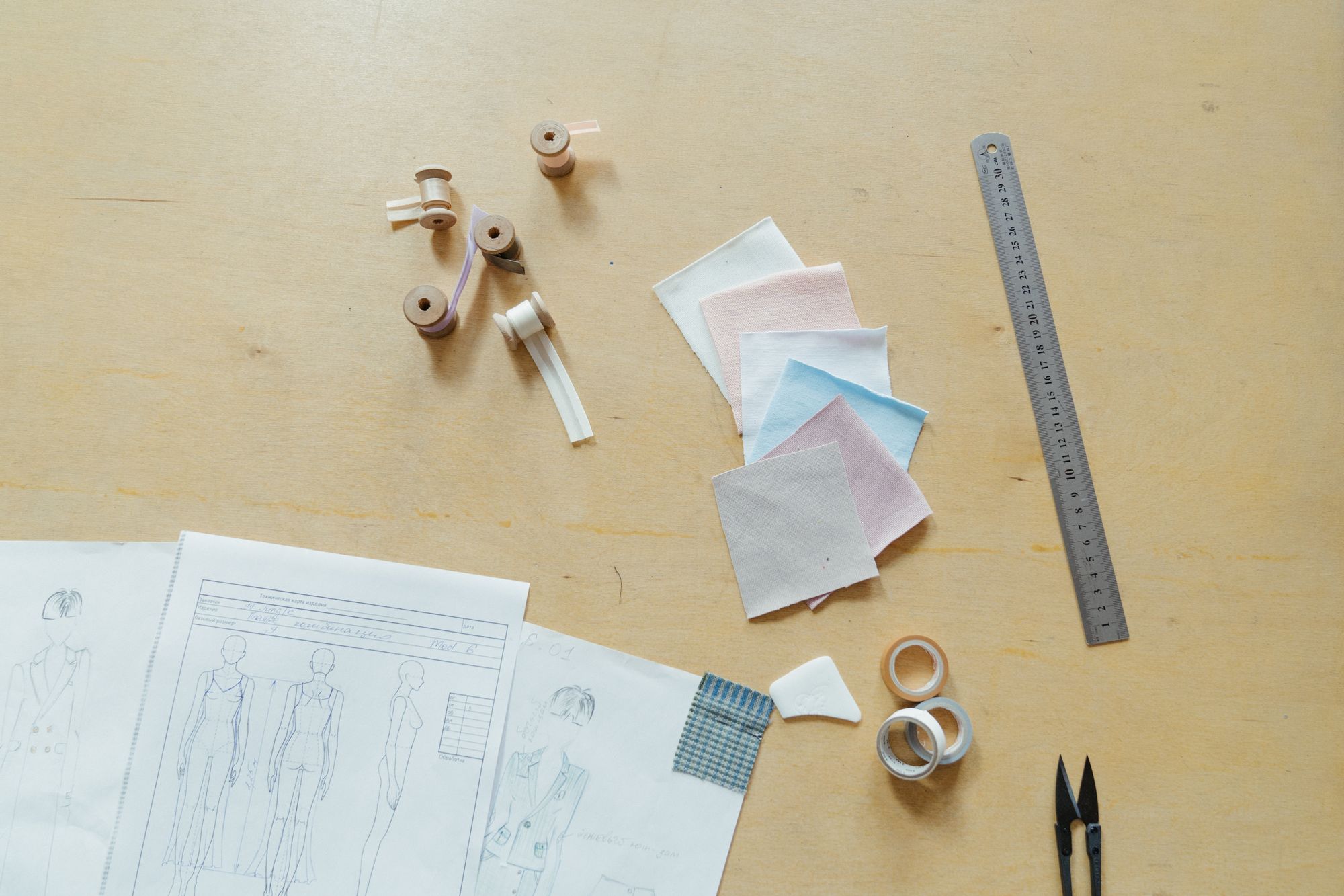 Sewing tools, fabric swatches and design sketches on a work table